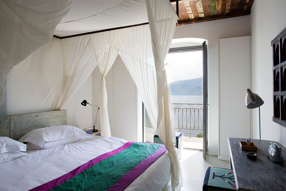 Four postered bed with netting and open door with view to sea in Ithaca villa Greece