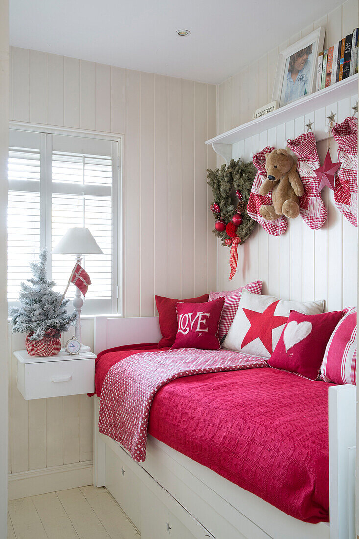 Rot gepolstertes Tagesbett mit Weihnachtsstrümpfen in einem Londoner Familienhaus England UK