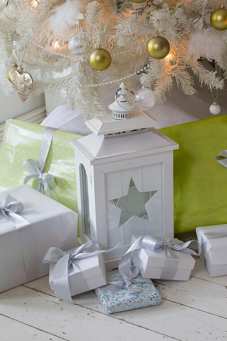 Sternförmige Laterne mit eingepackten Geschenken unter dem Weihnachtsbaum in einem Einfamilienhaus im Süden Londons England UK