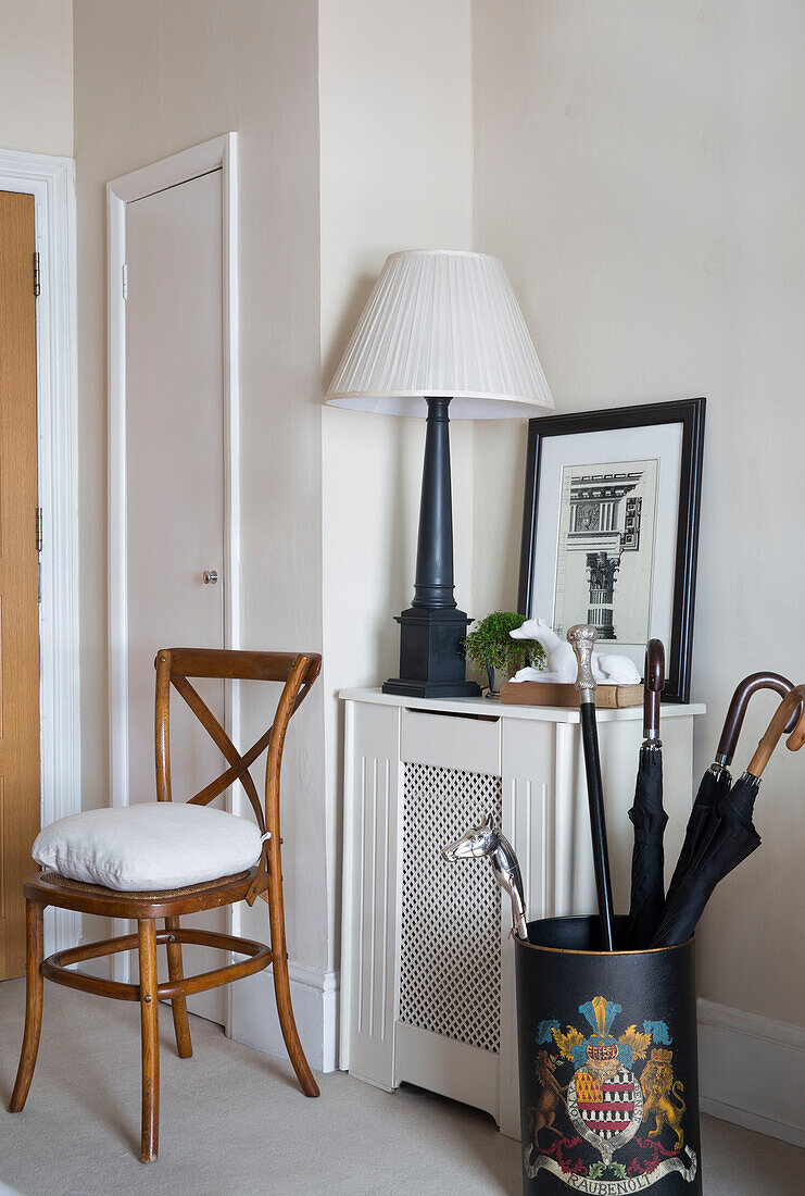 Wooden chair and umbrella stand in hallway of London townhouse apartment UK