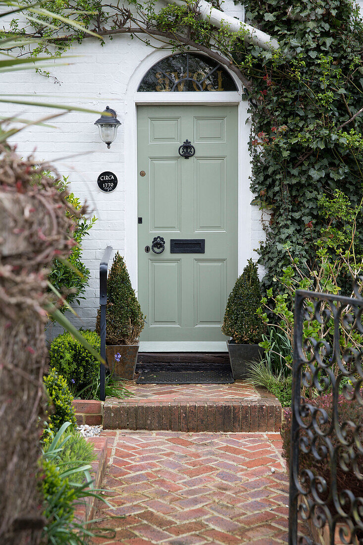 Light green front door and brick path to Sussex home England UK