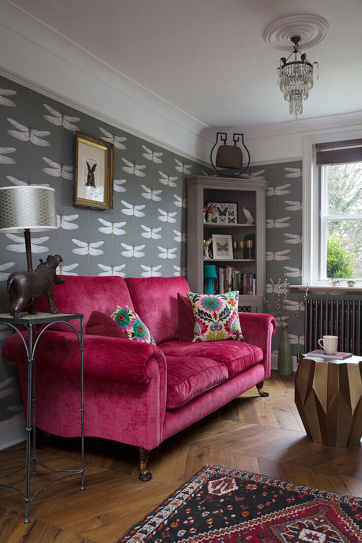 Neuartiger Lampenfuß und rosa Sofa mit Eckschrank und Libellen-Tapete in einem Haus in Sussex, England UK