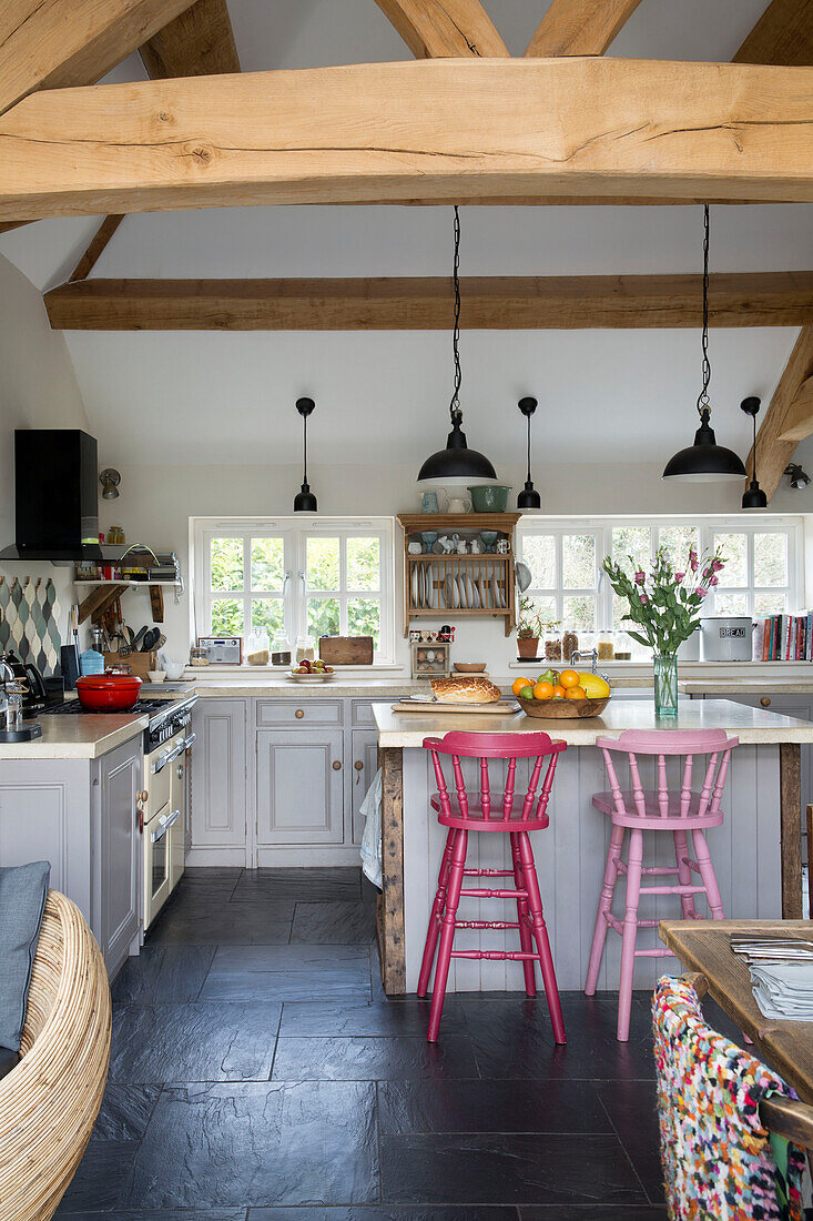 Painted pink bar stools in open plan beamed Sussex kitchen England UK