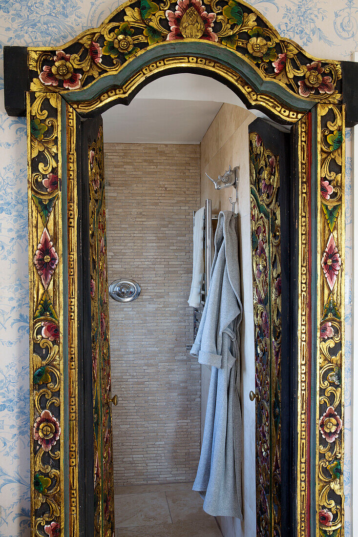 Blick durch einen dekorativen, geblümten Türrahmen auf ein Badezimmer in einem Haus in Sussex, England, UK