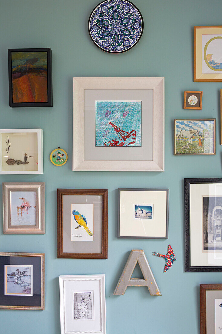 Collection of framed artwork and letter 'A' on light blue wall in Kelso home Scotland UK