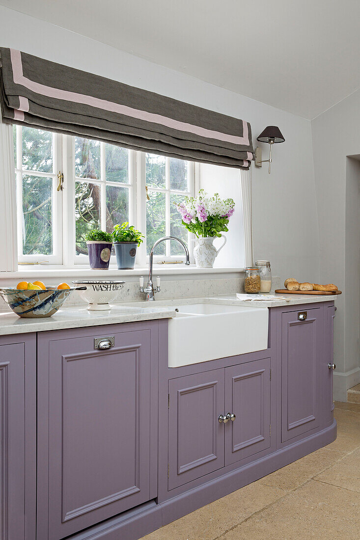 Lilac fitted butler sink at window in Gloucestershire kitchen England UK
