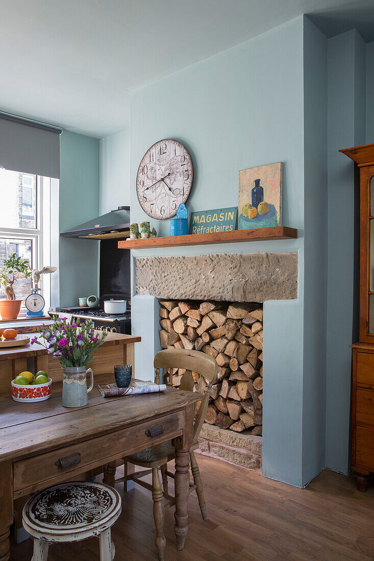 Uhr über einem Regal mit Brennholz in einer hellblauen Küche in Yorkshire England UK