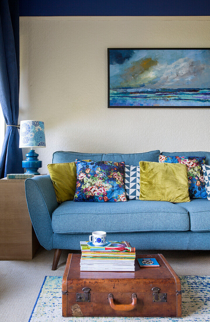 Assorted cushions on light blue sofa with seascape and vintage case in Yorkshire home England UK