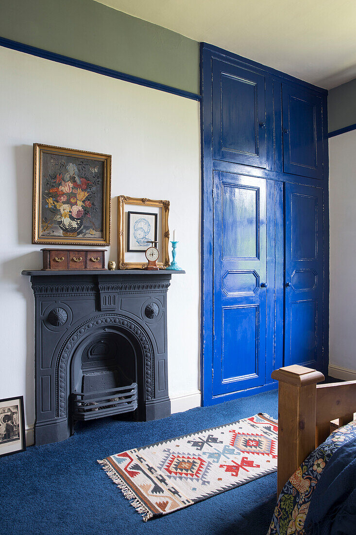 Patterned rug with original fireplace and blue painted built-in wardrobe in Yorkshire home England UK