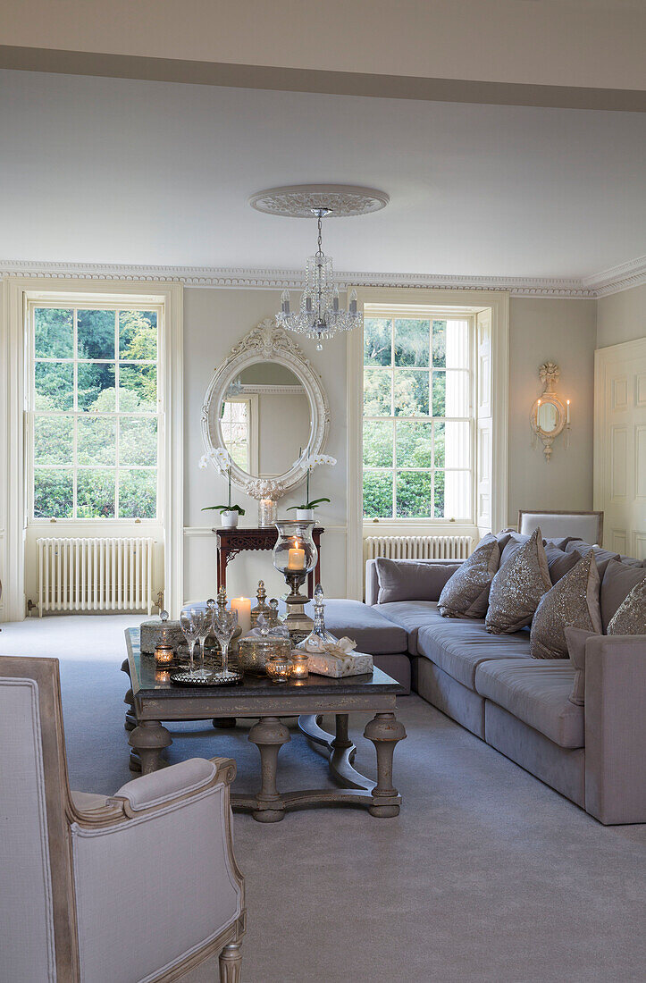Dekorativer ovaler Spiegel mit beleuchteten Teelichtern und Sofa im Wohnzimmer eines Landhauses in Kent, England, UK