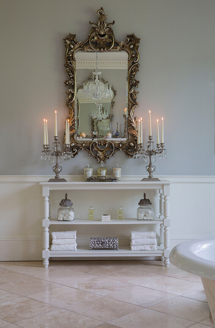 Beleuchtete Kerzen und dekorativer Spiegel mit Regal im Badezimmer eines Landhauses in Kent England UK