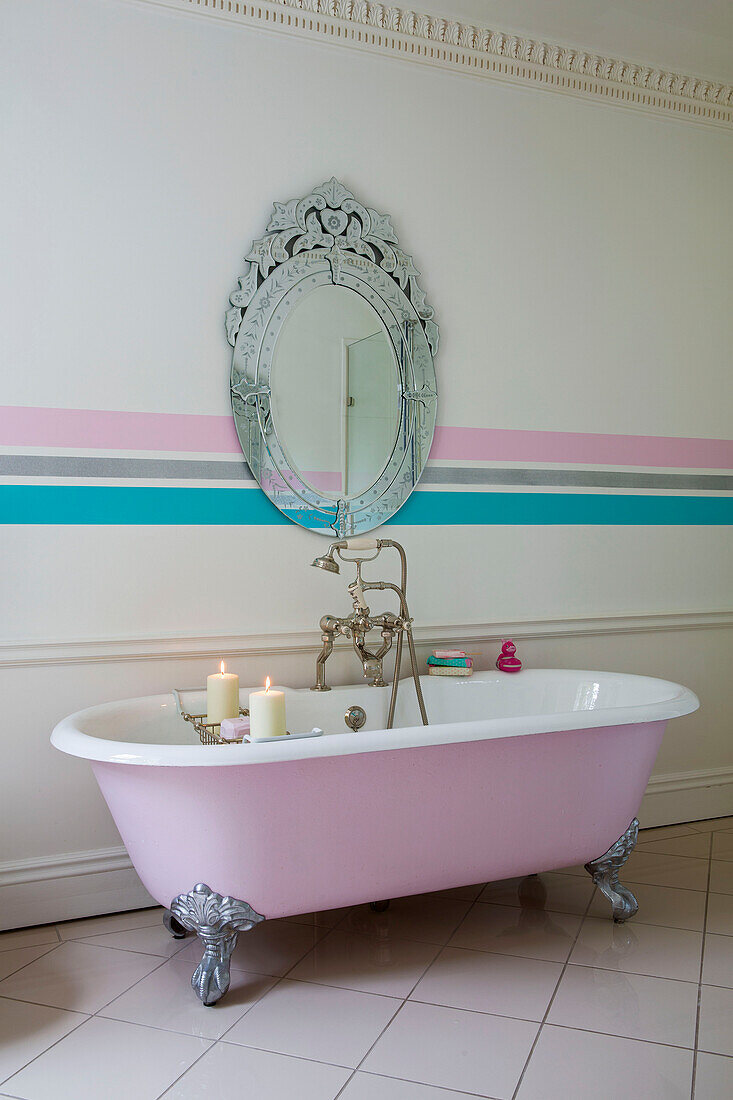 Pink freestanding bath with vintage mirror and wall strip in Kent country house England UK