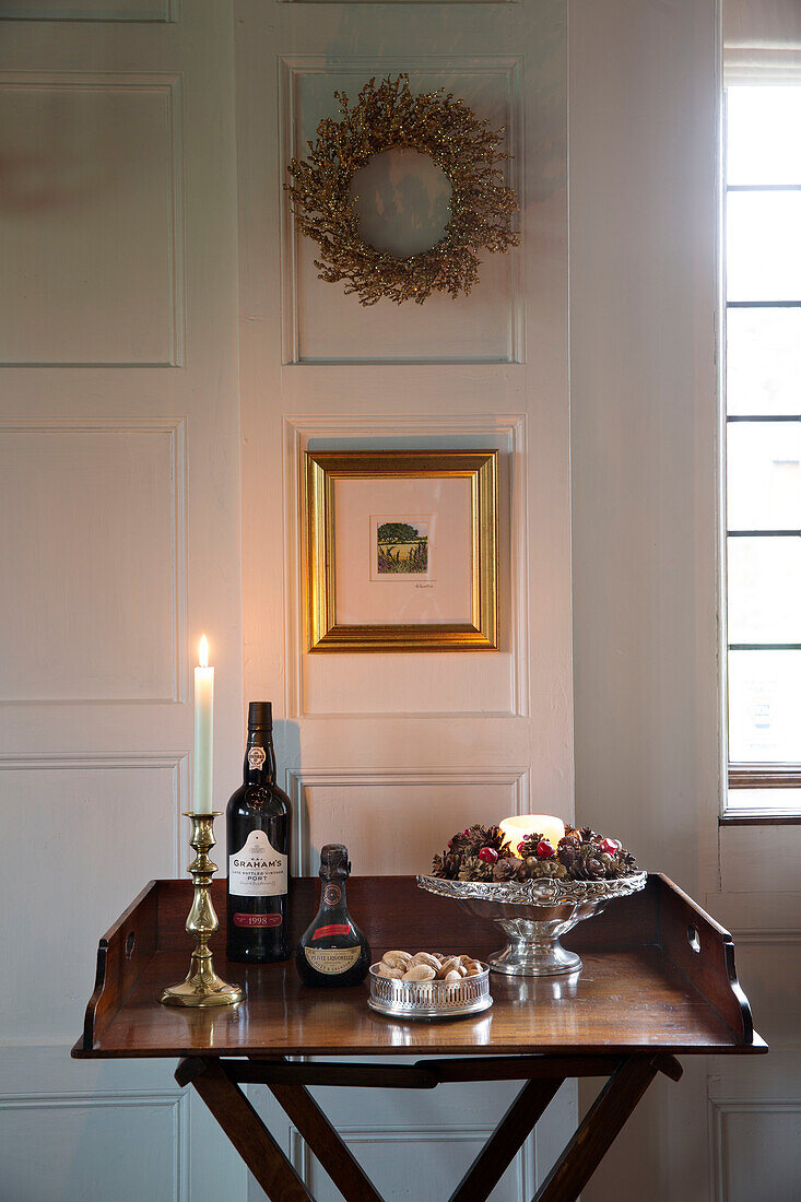 Red wine and nuts with lit candle on polished wooden side table in Hampshire farmhouse England UK