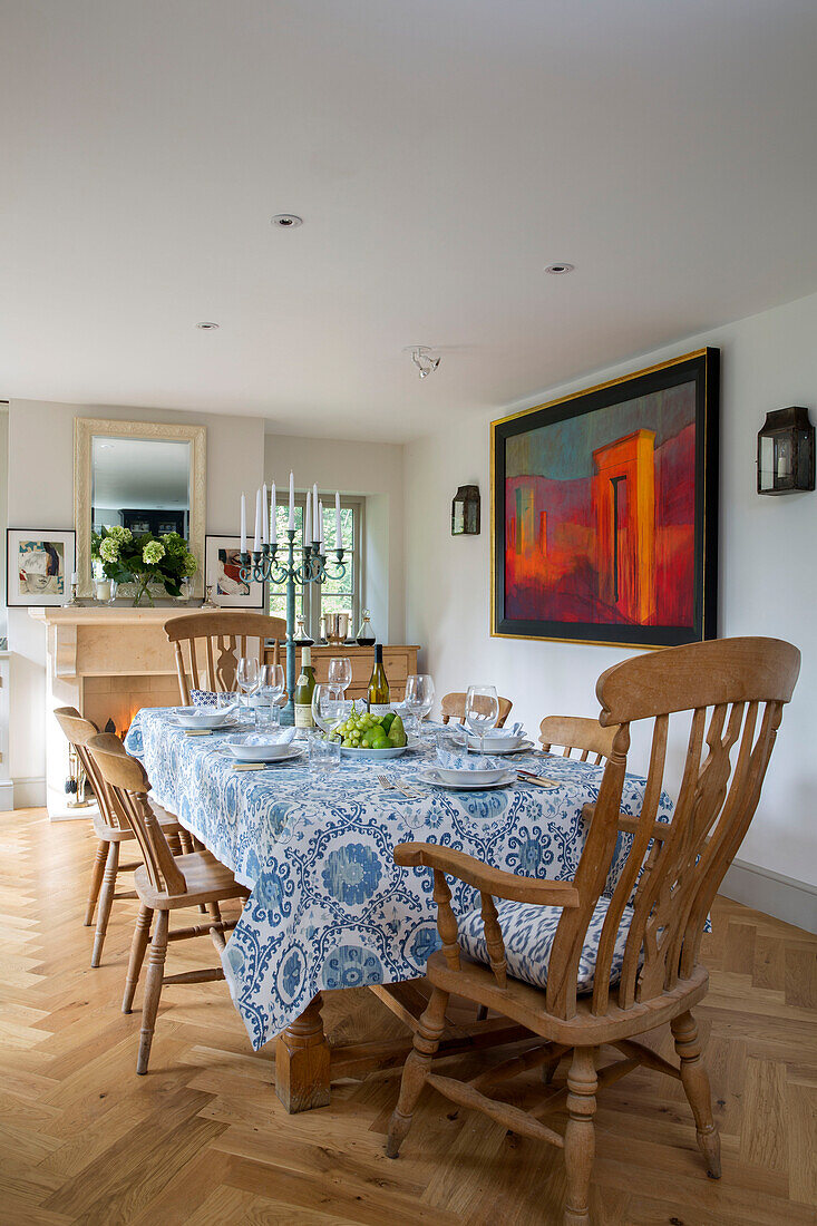 Holzstühle am Esstisch mit blau-weißer Tischdecke in einem Landhaus in Gloucestershire, UK