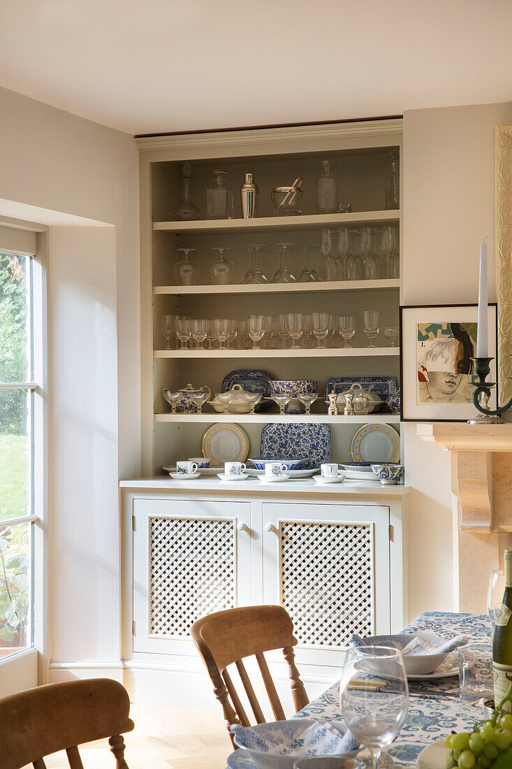 Glassware and crockery on shelves in dining room of Gloucestershire cottage UK
