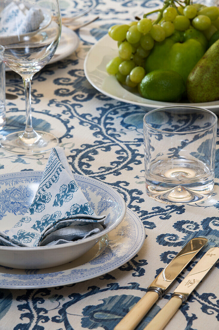 Blau-weiße Serviette in einer Schale mit Besteck und Weintrauben auf einem Esstisch in einem Cottage in Gloucestershire UK