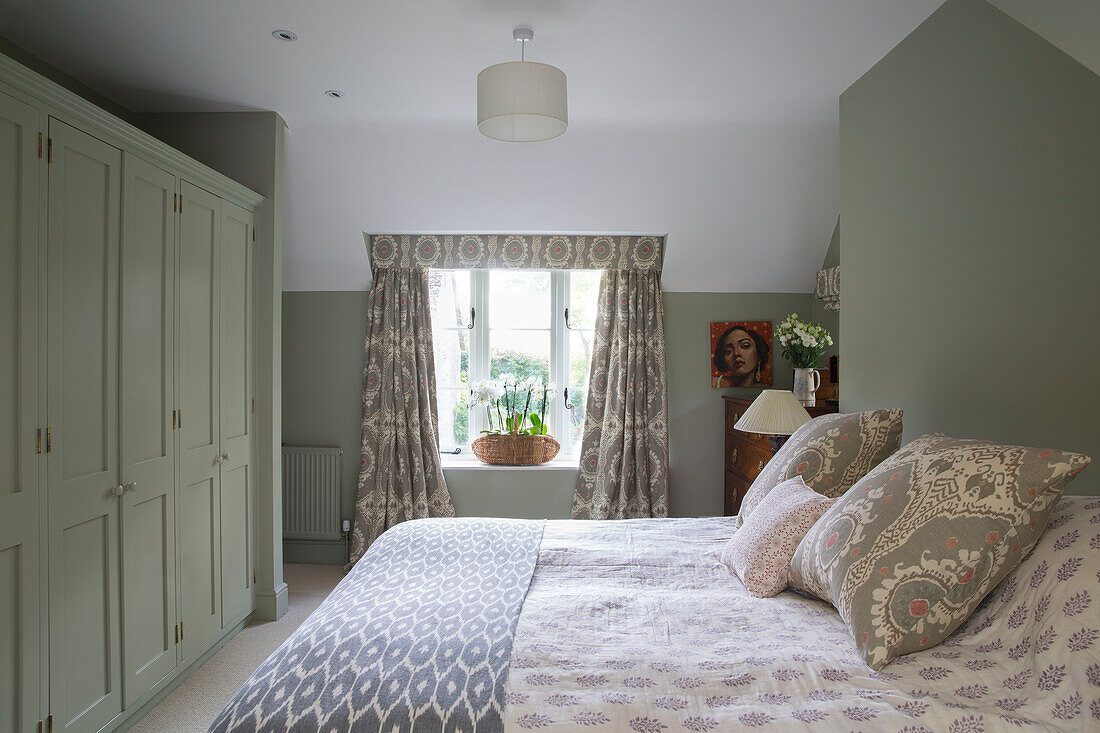 Double bed with contrasting fabric patterns in Gloucestershire bedroom UK