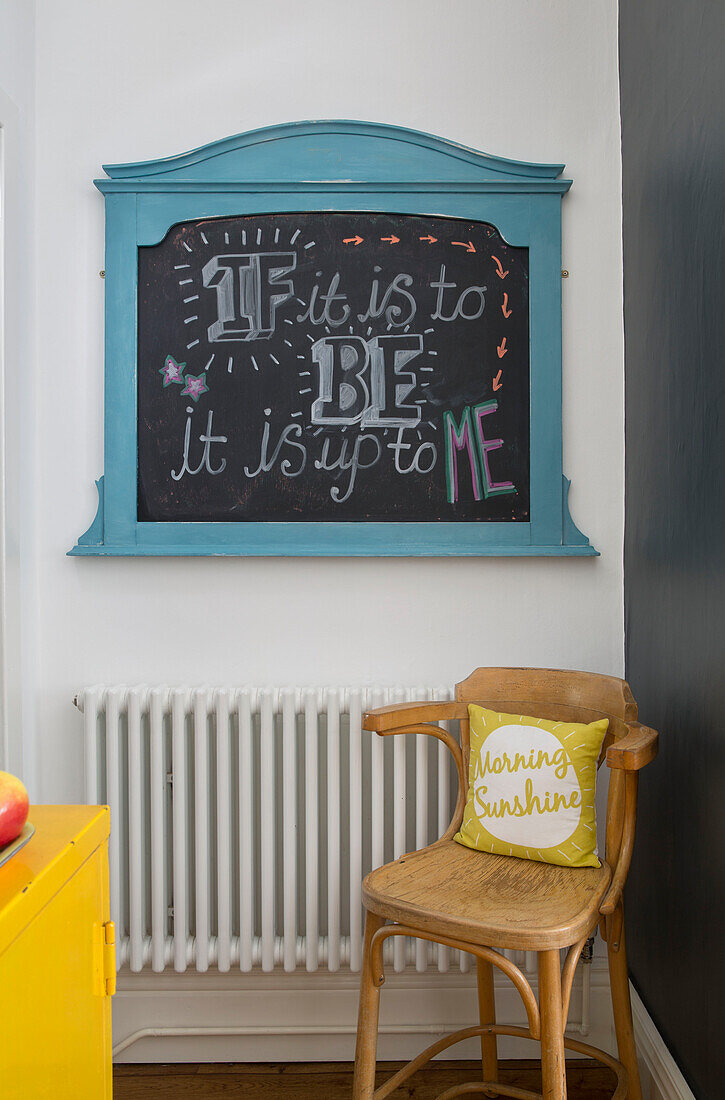 Chalkboard above chair at radiator in Brighouse kitchen West Yorkshire UK