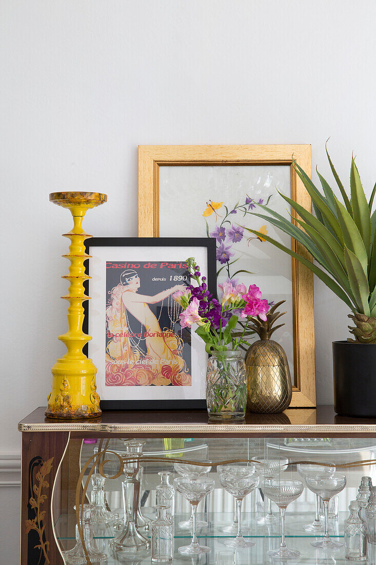 Framed prints and yellow candlestick with houseplant on display cabinet in Brighouse home West Yorkshire UK