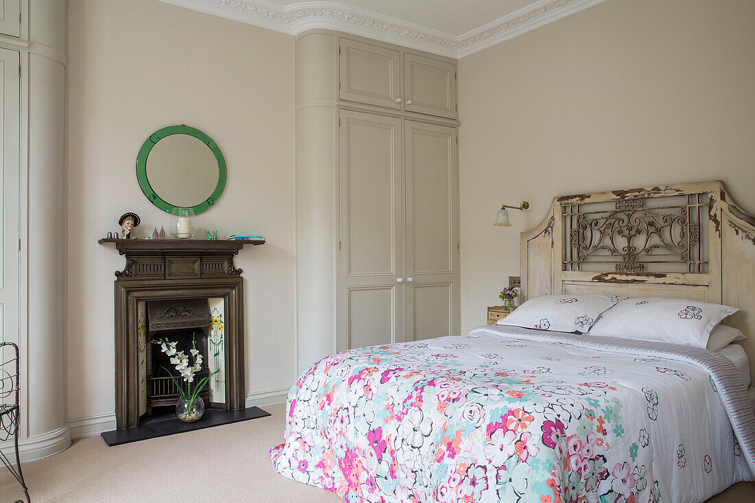 Geblümte Bettdecke auf einem Bett mit antikem Kopfteil in einem Londoner Stadthaus UK
