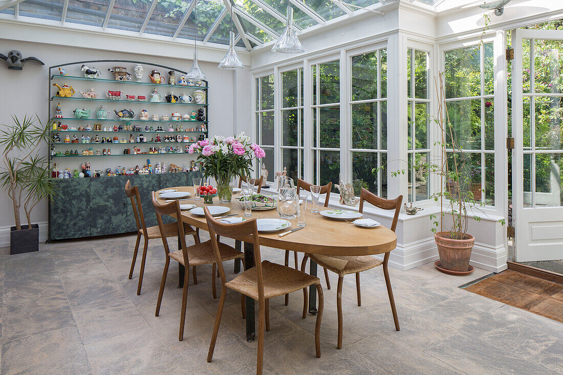 Esstisch und Stühle aus Holz mit einer Sammlung von Küchenutensilien in der Wintergartenerweiterung eines Londoner Stadthauses UK