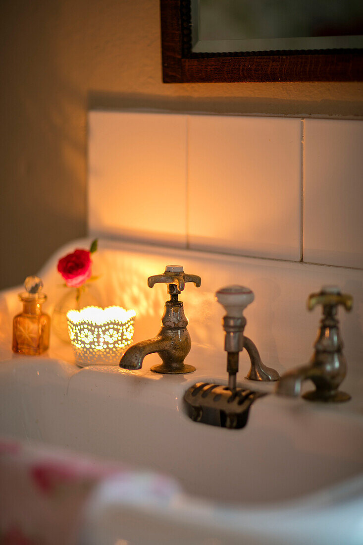 Beleuchtete Teelichter auf einem Waschbecken mit alten Wasserhähnen in einem georgianischen Landhaus Liverpool UK