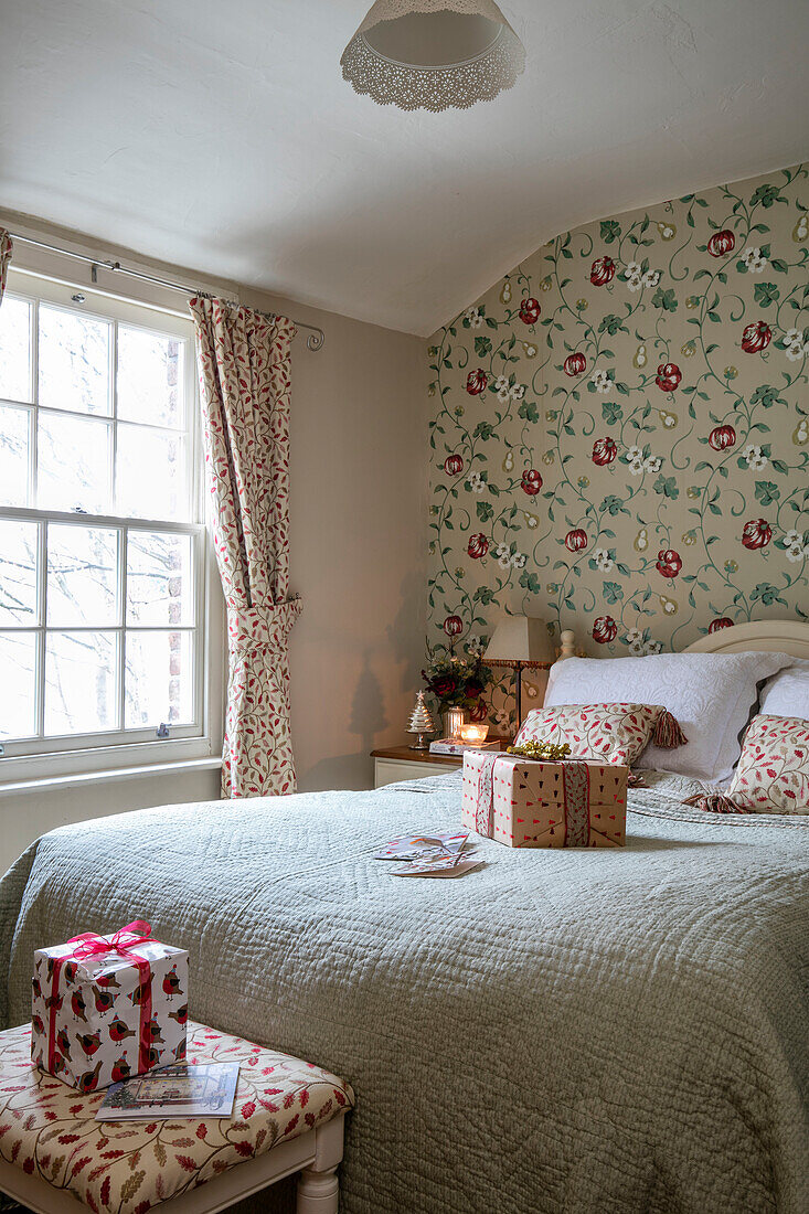 Christmas presents on double bed with floral wallpaper in Georgian cottage Liverpool UK