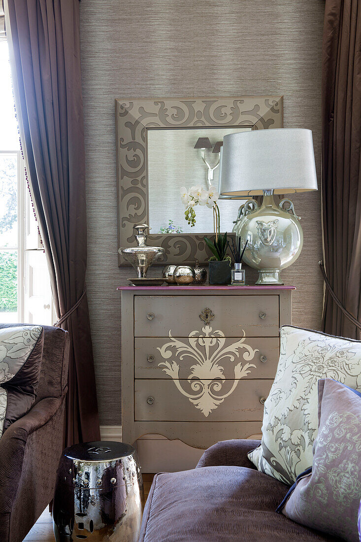 Gold metallic lamp and mirror on chest of drawers in detached Sussex country house UK