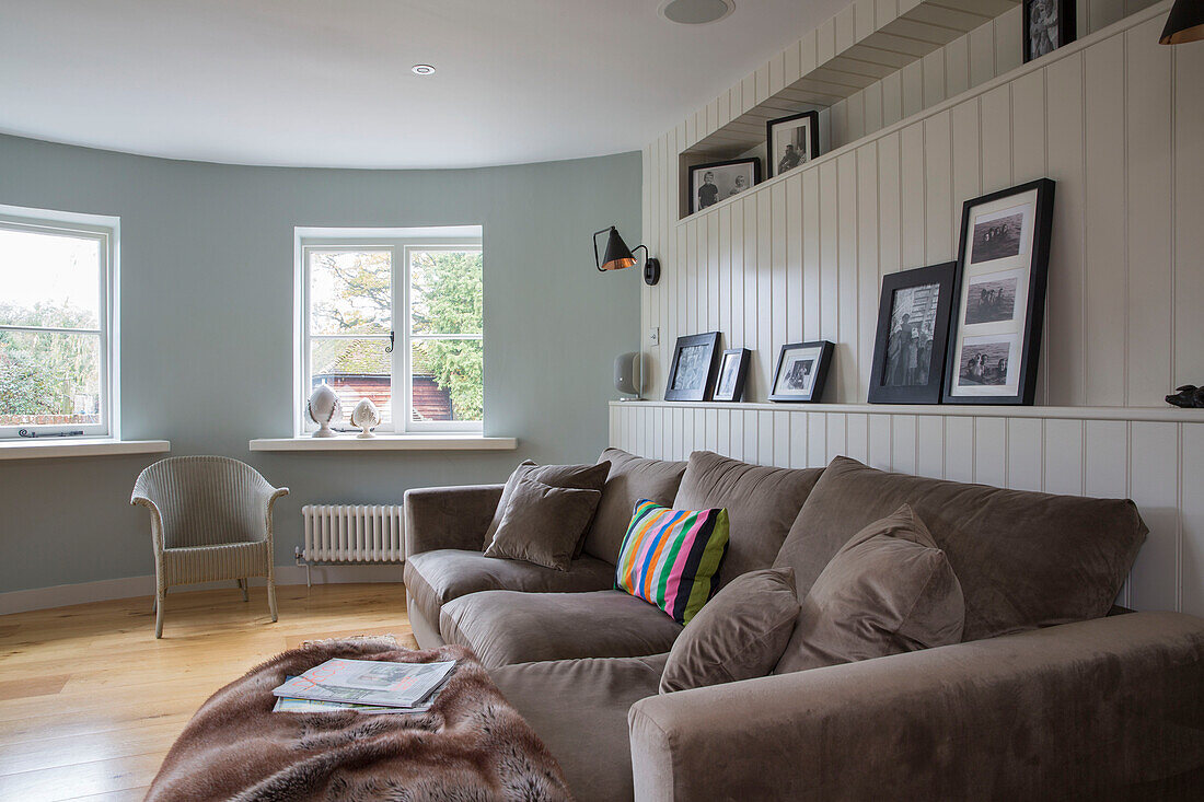 Hellbraunes Sofa mit schwarz-weiß gerahmten Fotos und Fenstern ohne Vorhänge in Oast house conversion Kent UK