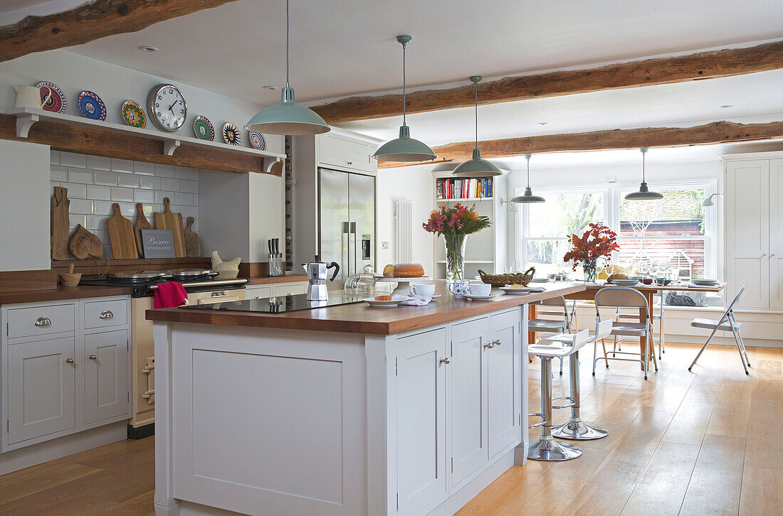 Pendelleuchten über einer weißen Kücheninsel in der offenen Küche eines umgebauten Gasthauses in Kent UK