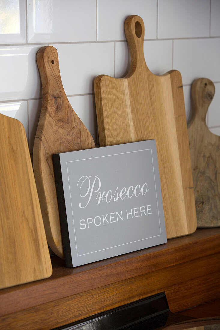 Chopping boards with sign reading 'Prosecco spoken here' in Oast house conversion Kent UK