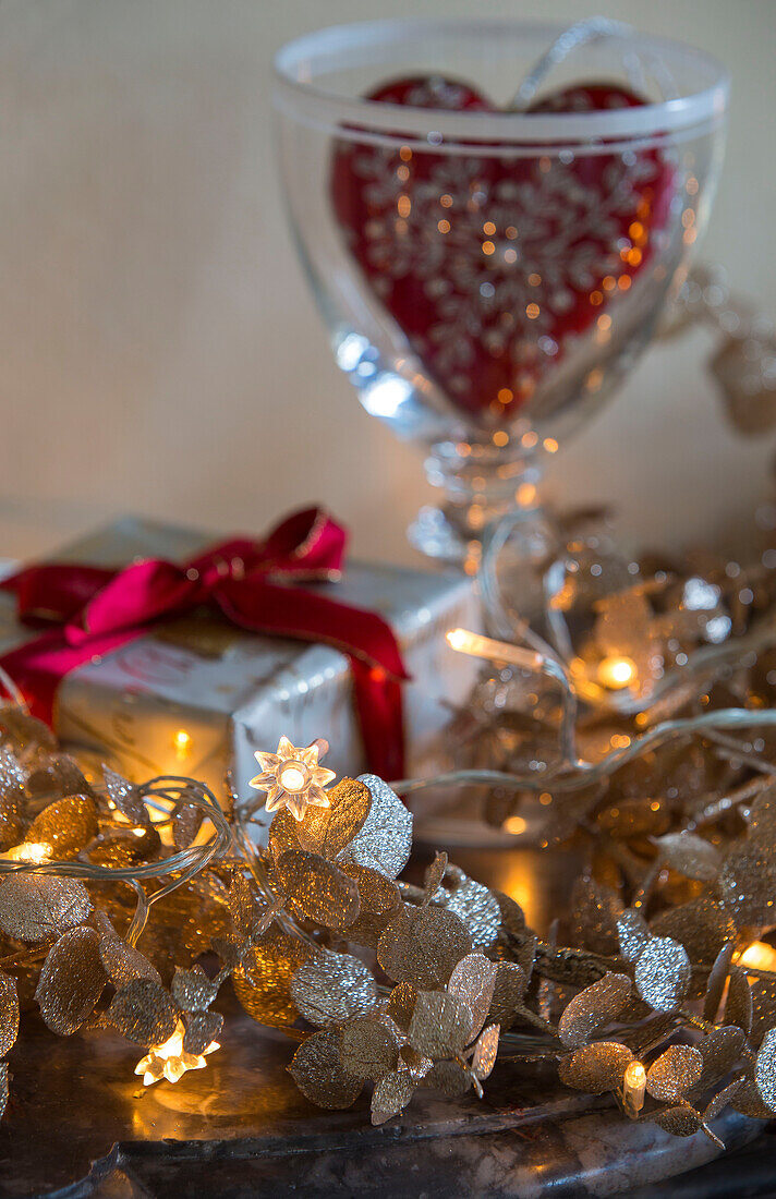 Gold fairylights with gift wrapped present and heart in glass London townhouse UK