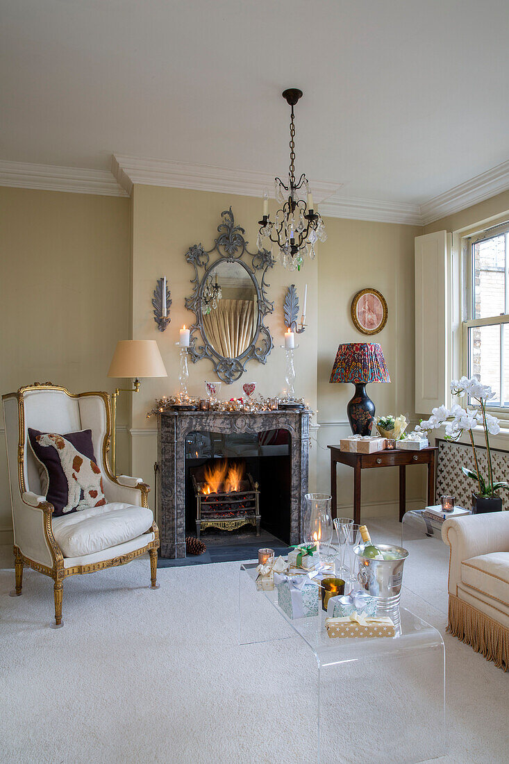 Gilt armchair at fireside with decorative mirror in London townhouse UK