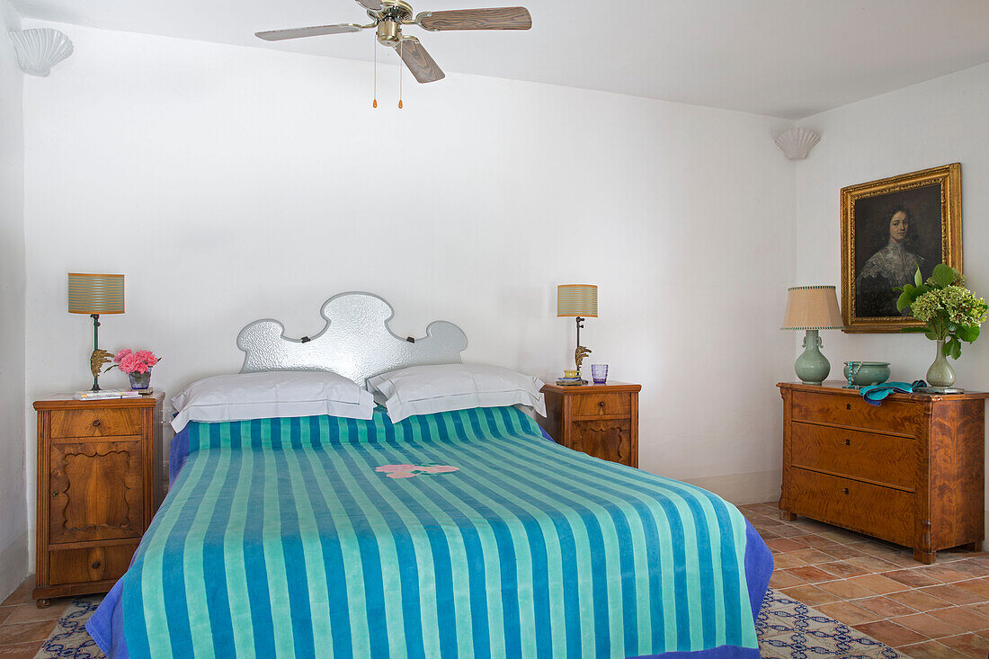 Brightly striped bed cover with wooden furniture on coastal villa Amalfi Italy