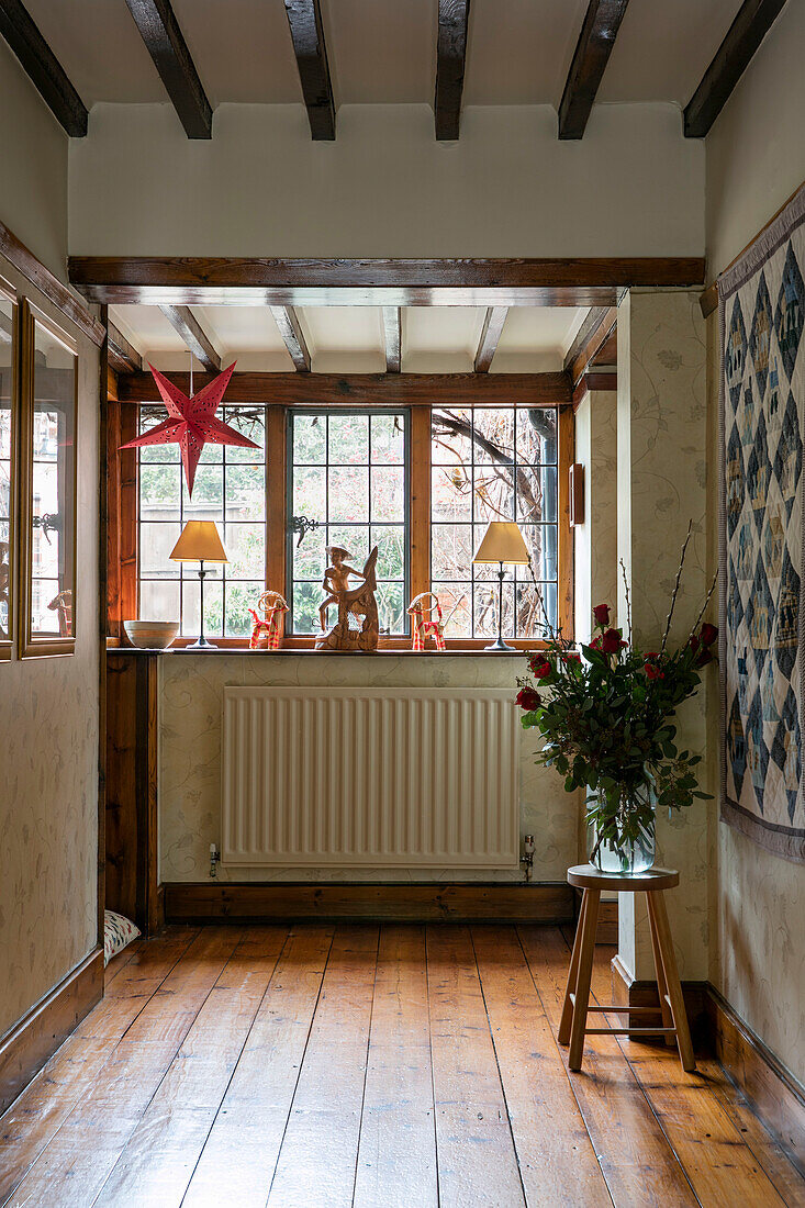 Patchworkdecke und Rosenvase am Fenster in einem Haus in Berkshire, Großbritannien