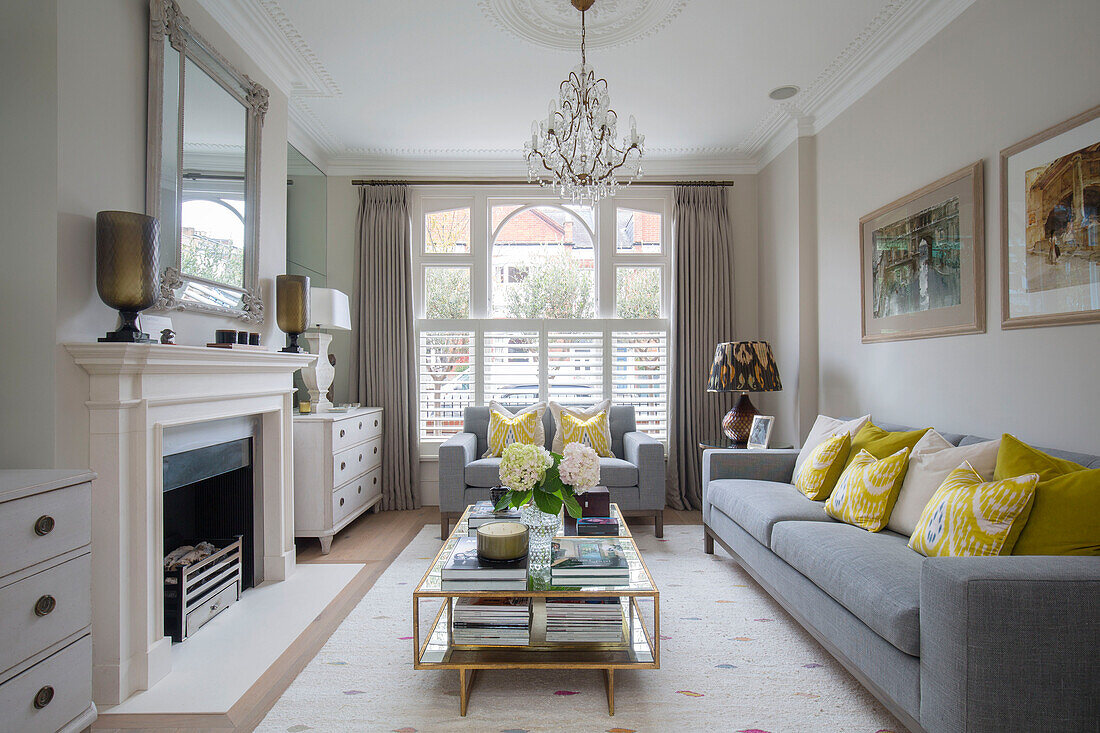 Gelbe Kissen auf grauen Sofas mit Vintage-Couchtisch im Wohnzimmer eines Londoner Stadthauses (UK)