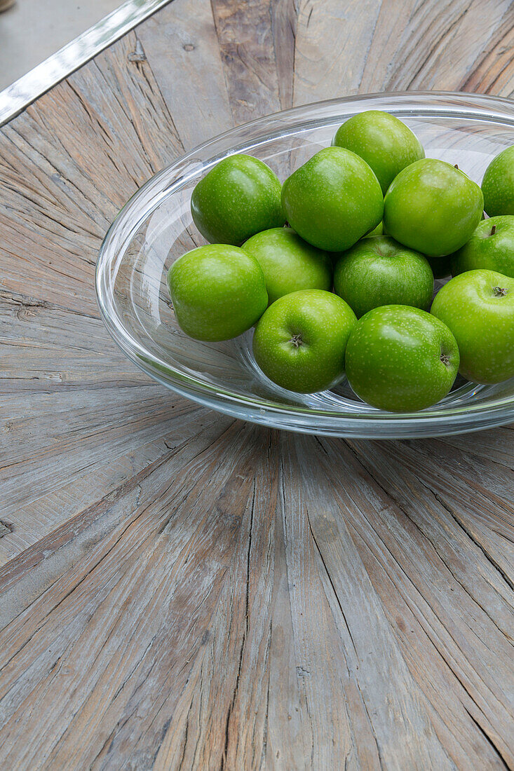 Glasschale mit grünen Äpfeln auf Holztischplatte in Londoner Stadthaus, UK