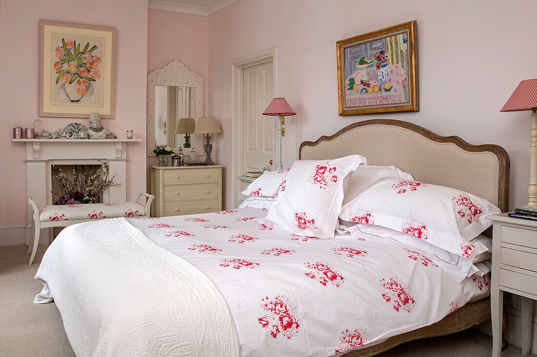 Red floral duvet and pillows on double bed in pink bedroom of Victorian terraced house South London UK