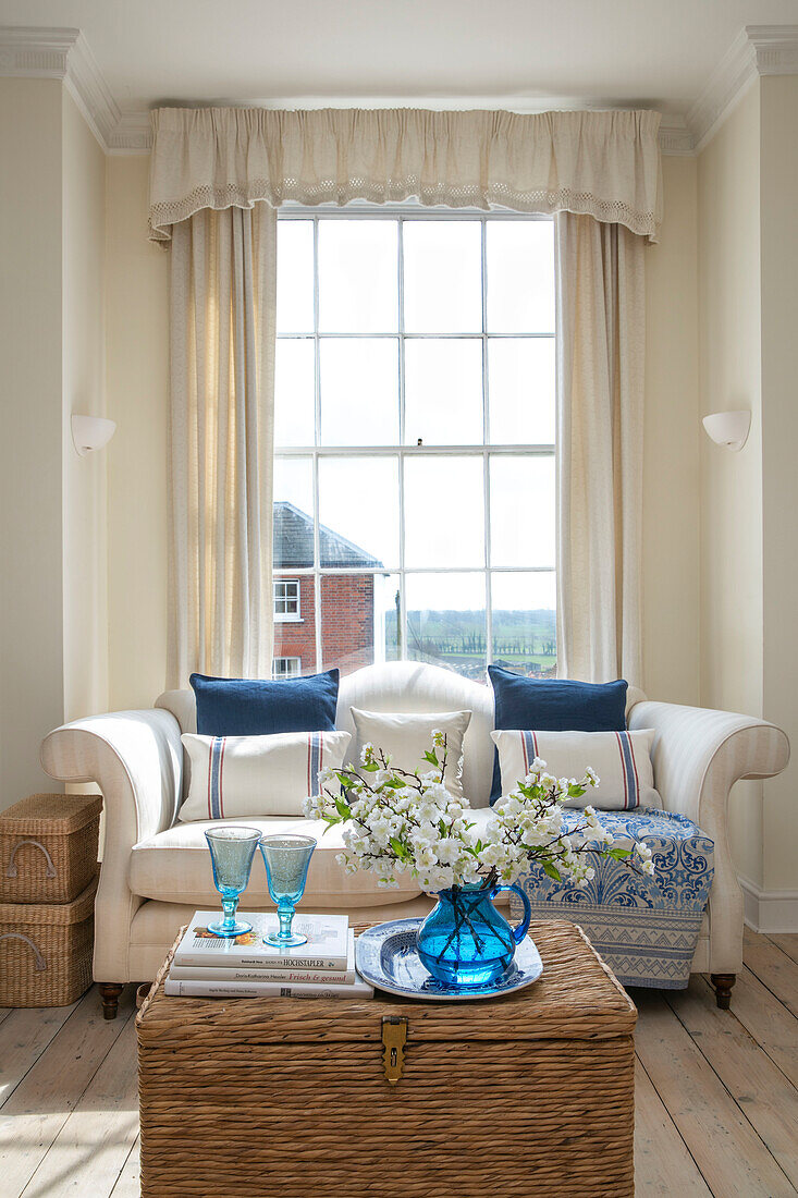 Schnittblumen und Weingläser mit Zweisitzer-Sofa am Fenster in einem Stadthaus in West Sussex UK