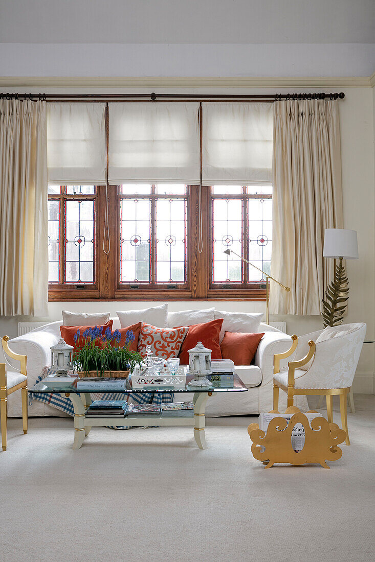 Geschnitzter Zeitschriftenständer mit weißem Sofa am Fenster und vergoldeten Stühlen in einem Stadthaus in West Sussex UK