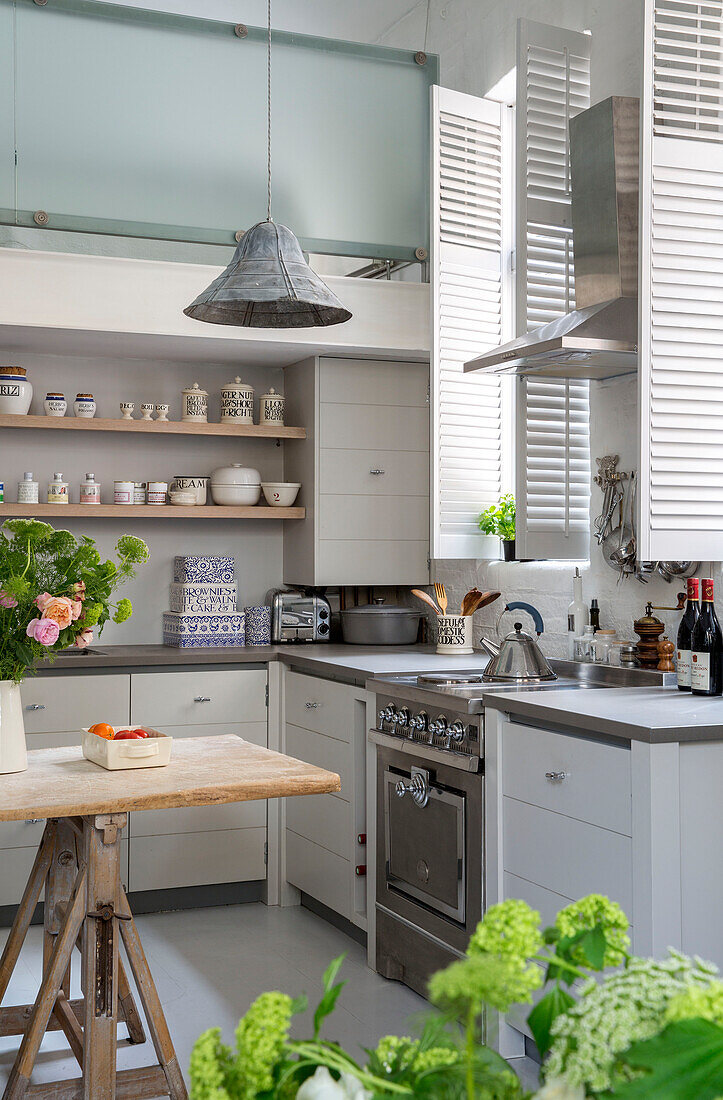 Pendelleuchte in einer Küche mit doppelter Höhe und Fensterläden in einem umgebauten Schulhaus in Südlondon UK