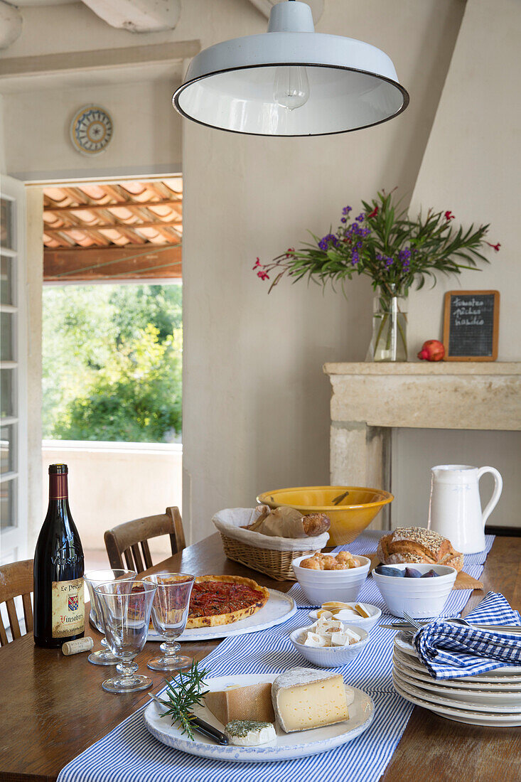 White pendant light above table set with food and drinks in 19th century Provencal farmhouse France