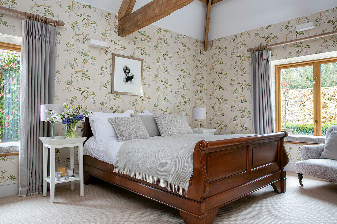 Gerahmtes Kunstwerk auf Blättertapete über einem Doppelschlittenbett in einer umgebauten Scheune in Gloucestershire UK