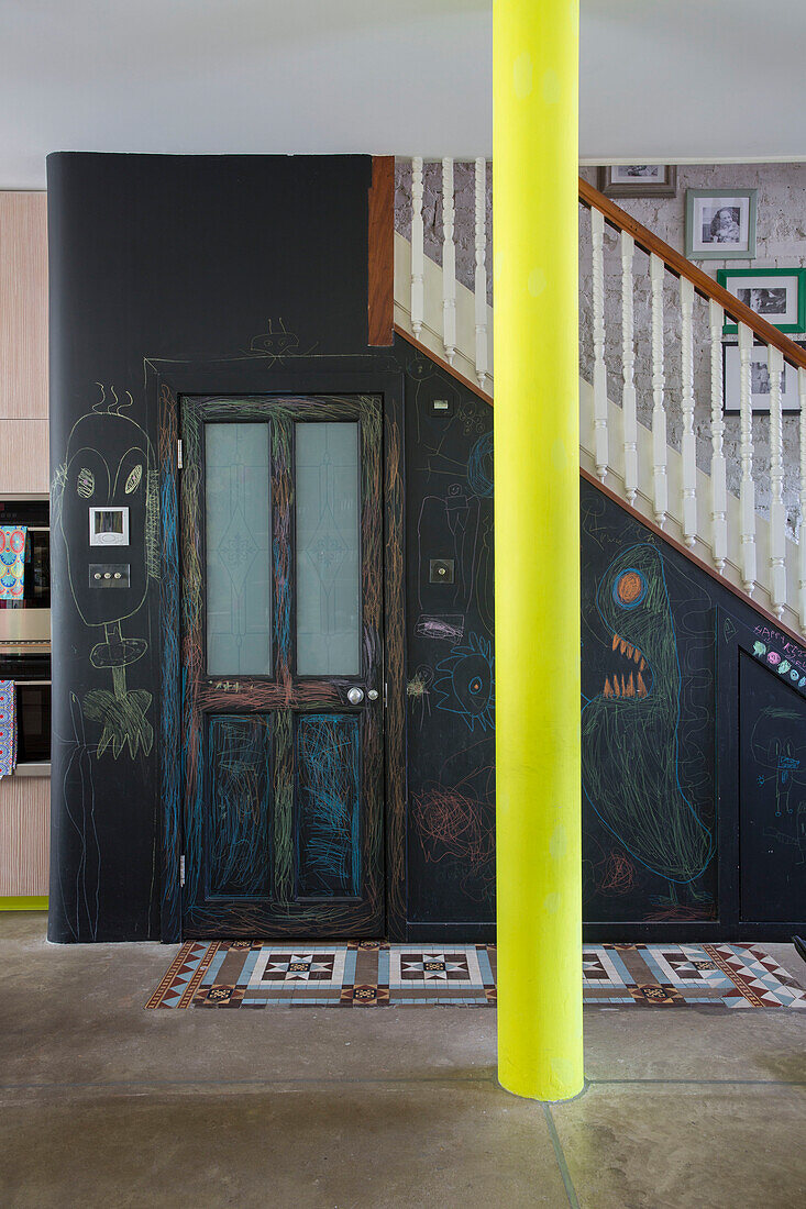 Chalk wall below banisters with bright yellow pillar in open plan Victorian London townhouse UK
