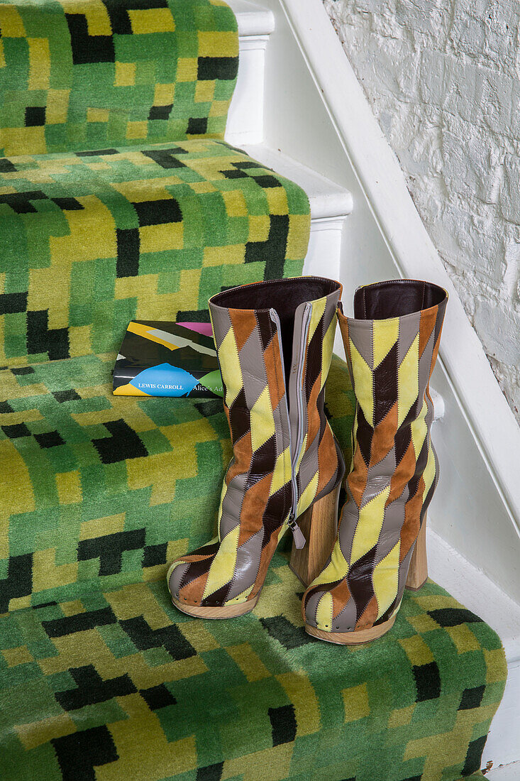 High heeled boots and books on black and green geometric carpeting in Victorian London townhouse UK