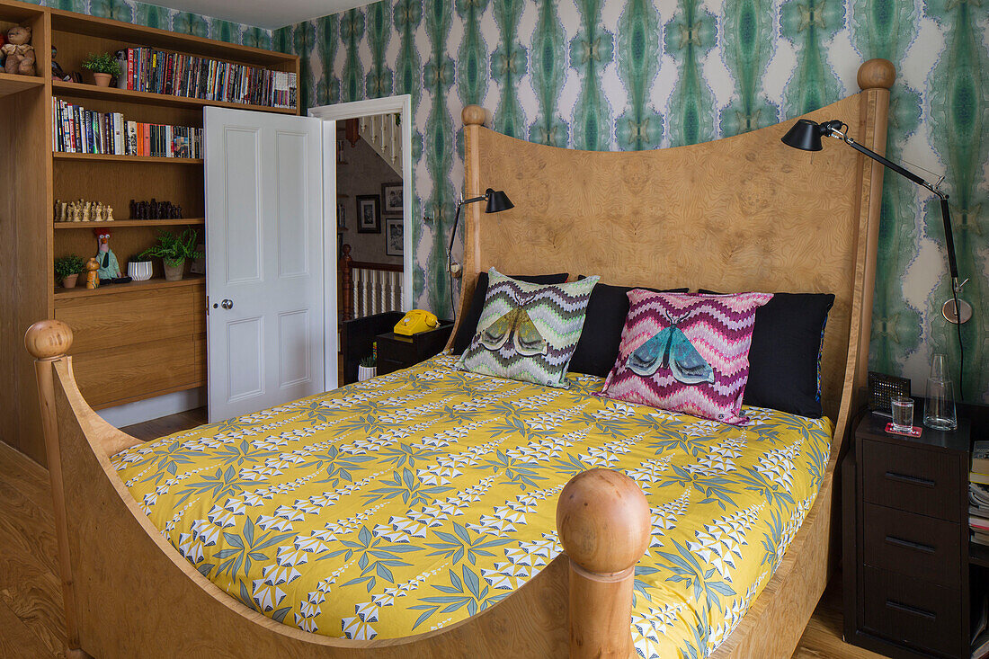 Tropisches Mobiliar auf Holzbett mit Bücherregal im Schlafzimmer eines viktorianischen Londoner Stadthauses UK