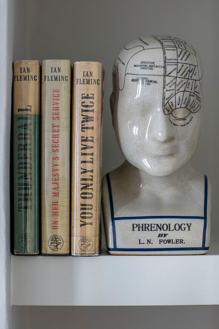Phrenologischer Kopf und Bücher von Ian Fleming auf einem Regal in einem Londoner Haus UK
