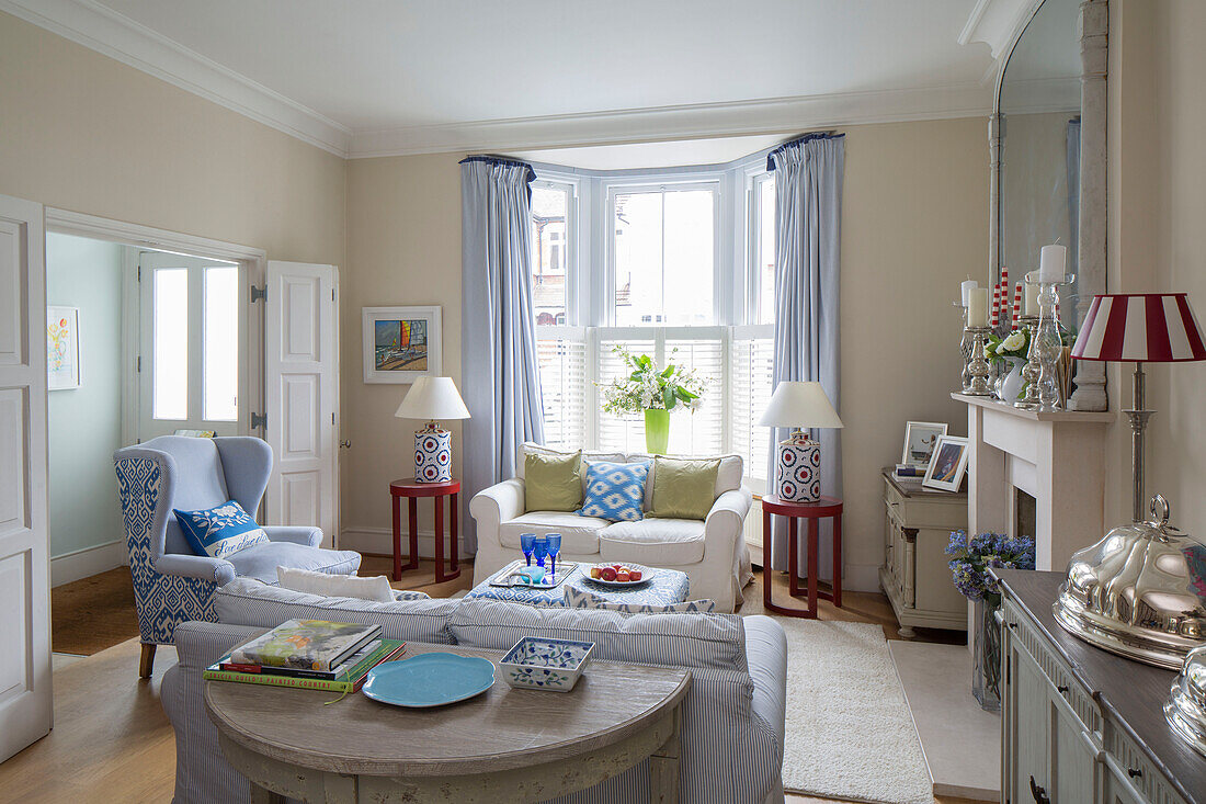 Pair of lamps with light blue curtains at bay window in living room of Victorian terrace house South London UK