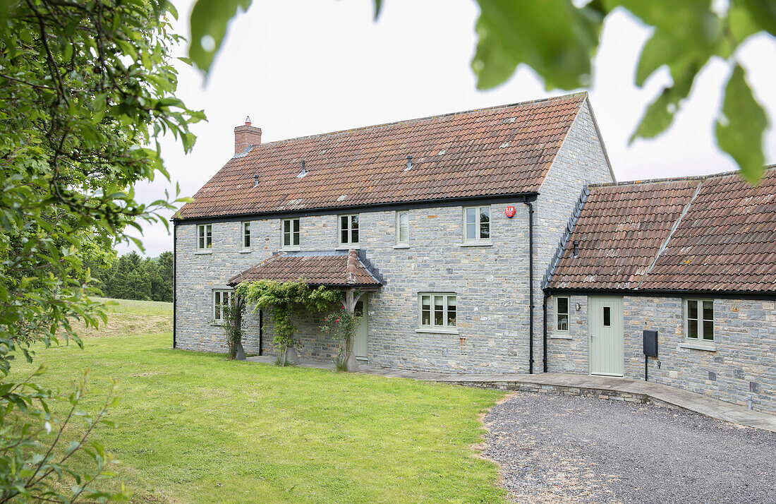 Steinfassade mit Ziegeldach und Veranda eines Bauernhauses in Somerset, UK