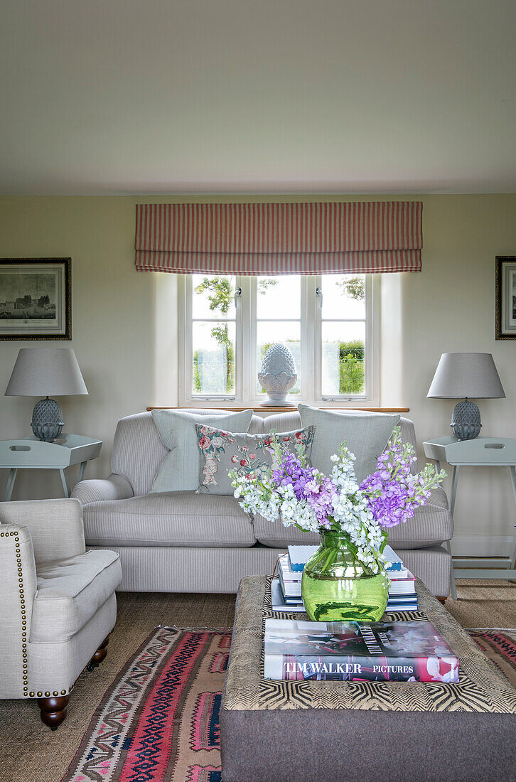 Cut flowers on ottoman with sofa and matching lamps in window of Somerset farmhouse UK
